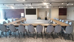 Une salle de conférence avec une longue table, des chaises, un écran de projection et une moquette à motifs.