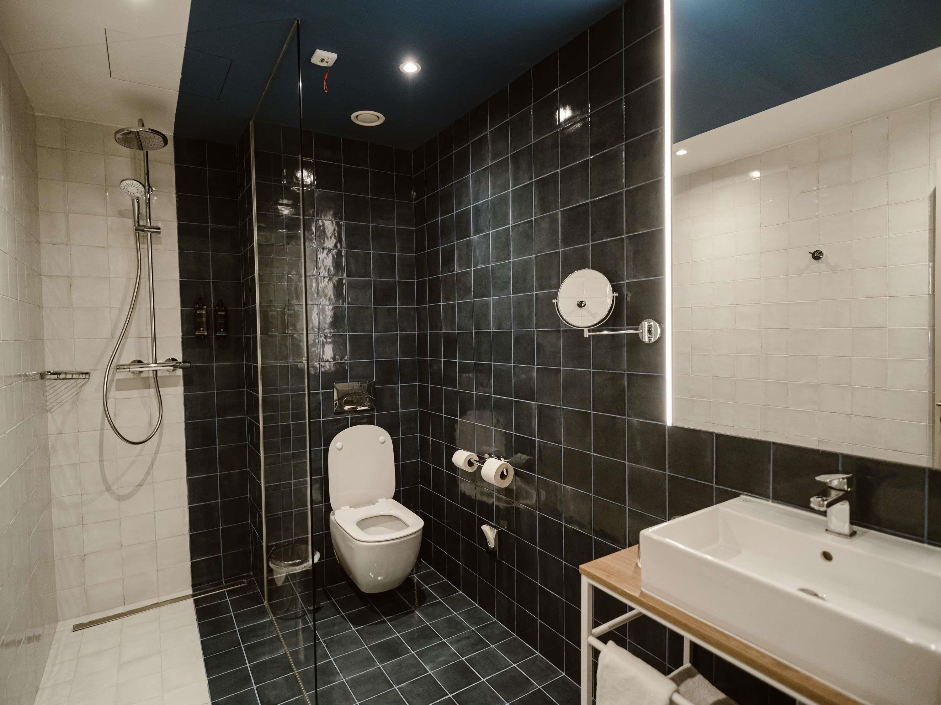 A modern bathroom with a shower, toilet, and sink.
