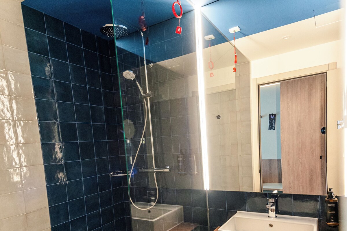 Une salle de bain moderne avec une douche à parois de verre, un lavabo blanc et un miroir au-dessus.