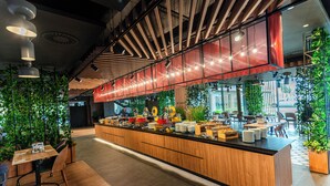 Un espace cuisine moderne doté d’un long comptoir, de divers appareils de cuisine et d’un coin repas avec des tables et des chaises.