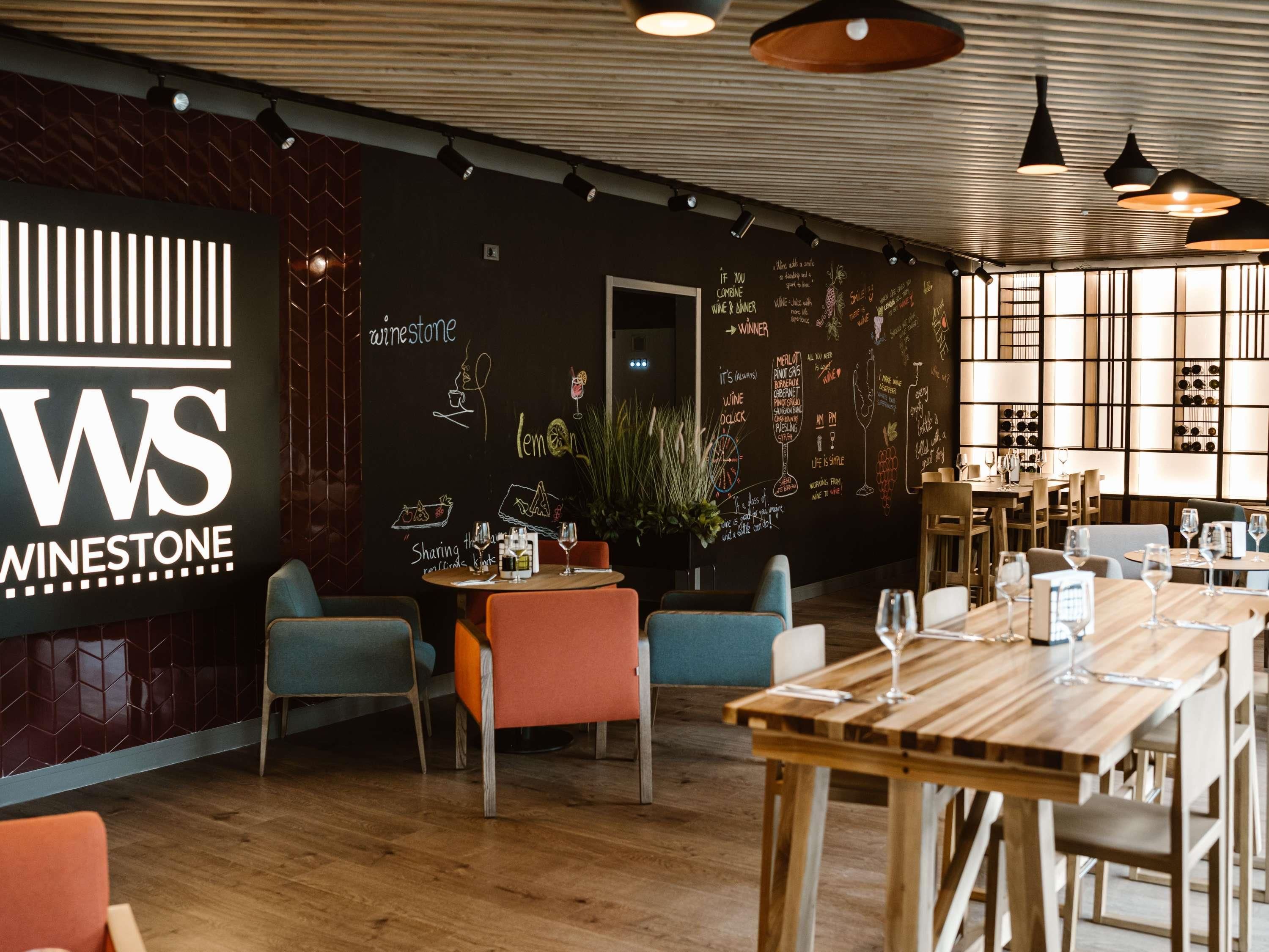 A restaurant interior with a chalkboard menu, wooden tables, and chairs.