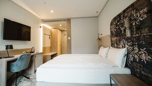 Une chambre d’hôtel moderne dotée d’un grand lit, d’un bureau avec une chaise, d’une télévision à écran plat et d’un espace douche.
