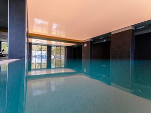 A modern indoor swimming pool with clear glass walls, a clean design, and a view of the outside. - Mercure Sibiu Arsenal (Sibiu)