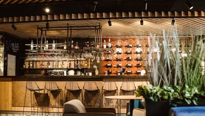 A bar area with multiple seating options, a variety of bottles and glasses on display, and a wooden ceiling design. - Mercure Sibiu Arsenal (Sibiu)