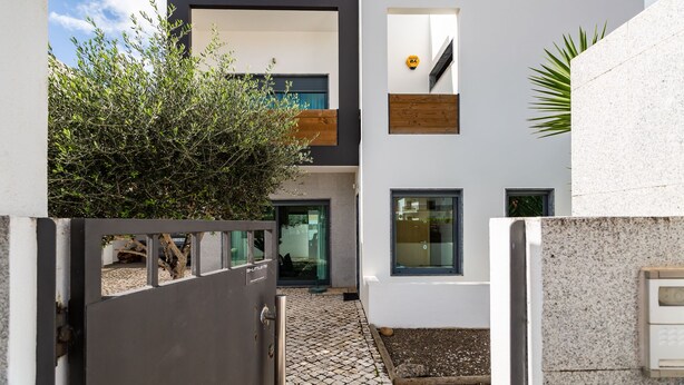 Ein modernes Gebäude mit Innenhof, inklusive Metalldrahtzaun, Baum und kleinem Gartenbereich.
