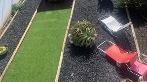 Ein Garten mit Kunstgrasanlage, einem Whirlpool und verschiedenen Blumentöpfen.