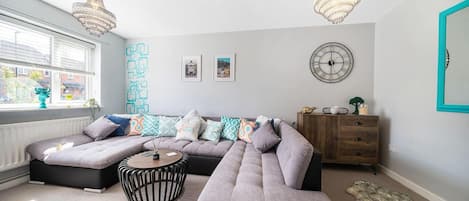 Una sala de estar moderna con un sofá modular, una mesa de centro redonda y un aparador de madera.