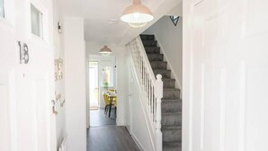 A hallway with a staircase, white doors, and a dining area in the background. - Spacious 3 bed House Garden Parking Wifi Smart tv (Coventry)