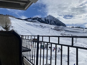 A snowy mountain landscape with a ski slope, ski lift, and a few skiers.