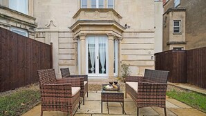 A patio with wicker furniture and a table with fruit. - Huge House Pool Table Parking Garden sky tv Wifi (Gloucester)