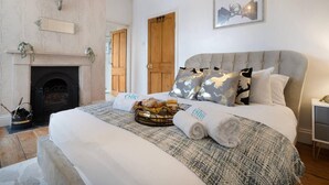A bedroom with a large bed, a fireplace, and a wooden door. - Huge House Pool Table Parking Garden sky tv Wifi (Gloucester)