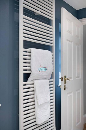 A white towel with 'esho' branding hanging on a white radiator in a room with blue walls and a white door. - Huge House Pool Table Parking Garden sky tv Wifi (Gloucester)