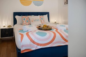 A neatly made bed with a blue headboard, multiple pillows, and a tray with breakfast items. - Lovely Little House, Free Parking, Smart tv, Wifi (Gloucester)