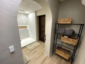 Bathroom features a shower area with a glass door and a wooden door leading to another room.