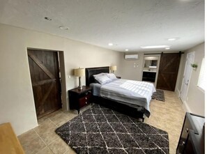 Relax in comfort with a large bed, nightstand, and air conditioning unit.