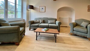 Ein Wohnzimmer mit einer Sofagarnitur, einem Couchtisch und einer Stehlampe.