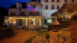 Ein Hotel mit gut beleuchtetem Eingang, einem sichtbaren Schild mit der Aufschrift "LANOISELEE" und einem Garten mit einer Laube.
