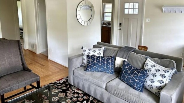 A living room with a grey sofa, patterned cushions, a round mirror, and a wooden coffee table. - Sunny Hilltop 2-BR Top Floor in Arlington (Arlington)