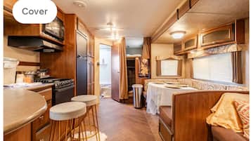 Een koelkast, een kookplaat, kookgerei, borden en bestek, keukenrol