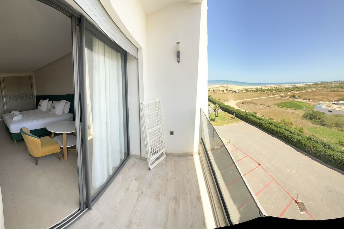 A balcony with a bed, a small table, and a chair.