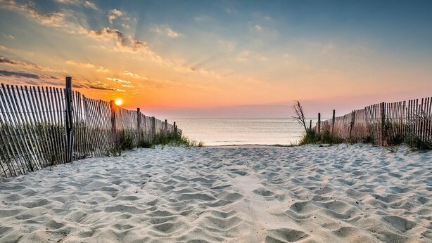 A sandy beach with a wooden fence and a sunset in the background. - Pickleball Dream - All New, Modern Condo in Sea Colony. 10mins walk to the beach (South Bethany)