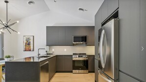 A modern kitchen with stainless steel appliances, a microwave, and a large refrigerator. - Pickleball Dream - All New, Modern Condo in Sea Colony. 10mins walk to the beach (South Bethany)