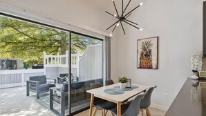 A modern kitchen with a large window, a dining area with a table and chairs, and a ceiling light fixture. - Pickleball Dream - All New, Modern Condo in Sea Colony. 10mins walk to the beach (South Bethany)