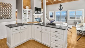 A spacious kitchen with white cabinetry, a black countertop, and a wooden ceiling. - Just Like Heaven - Beachfront (Crawfordville)