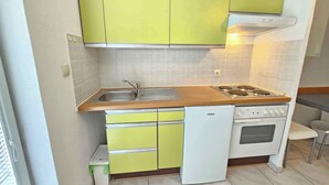 Een kleine keuken met een spoelbak, fornuis en vaatwasser.