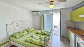 Een kleine slaapkamer met een enkel bed, een plafondventilator en een airconditioning.