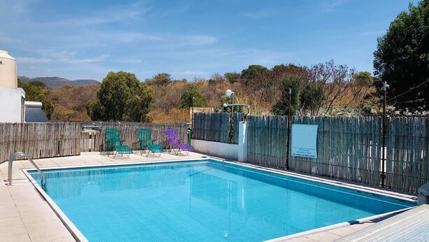 Una piscina rectangular con un borde de baldosas, rodeada por una valla de madera.