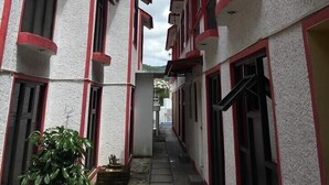 Un estrecho pasillo entre edificios con ventanas de marco rojo y paredes blancas.