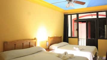 Habitación de hotel con dos camas, ventilador de techo y ventana con vista al exterior.