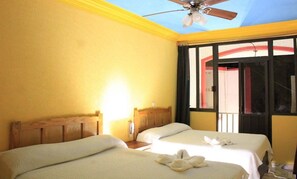 Habitación de hotel con dos camas, ventilador de techo y ventana con vista al exterior.