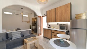 Una cocina moderna con armarios de madera, un refrigerador de acero inoxidable y una zona de comedor con una mesa y sillas blancas.