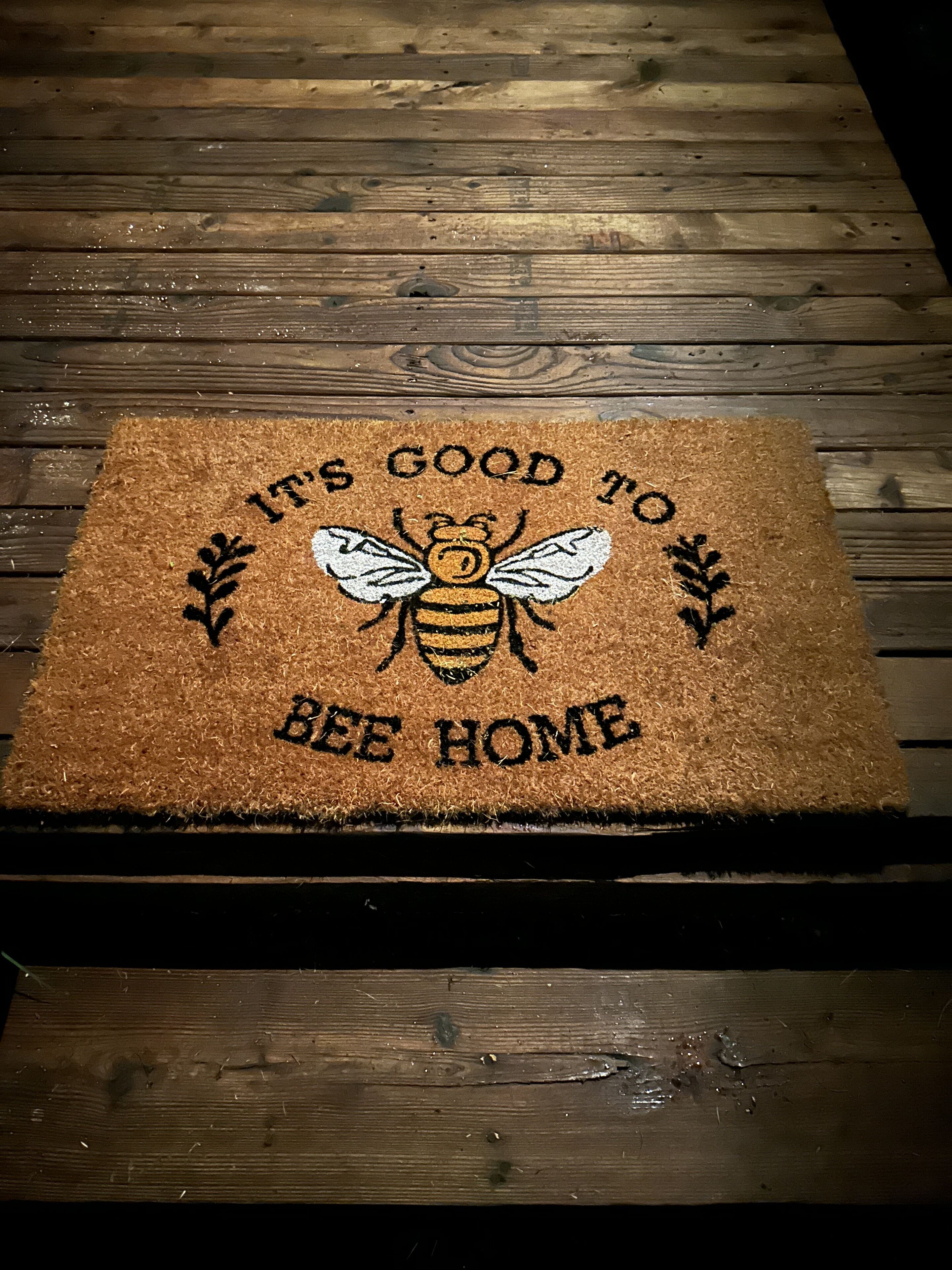Un estri de porta amb un disseny d'abella i la frase "It's good to bee home".