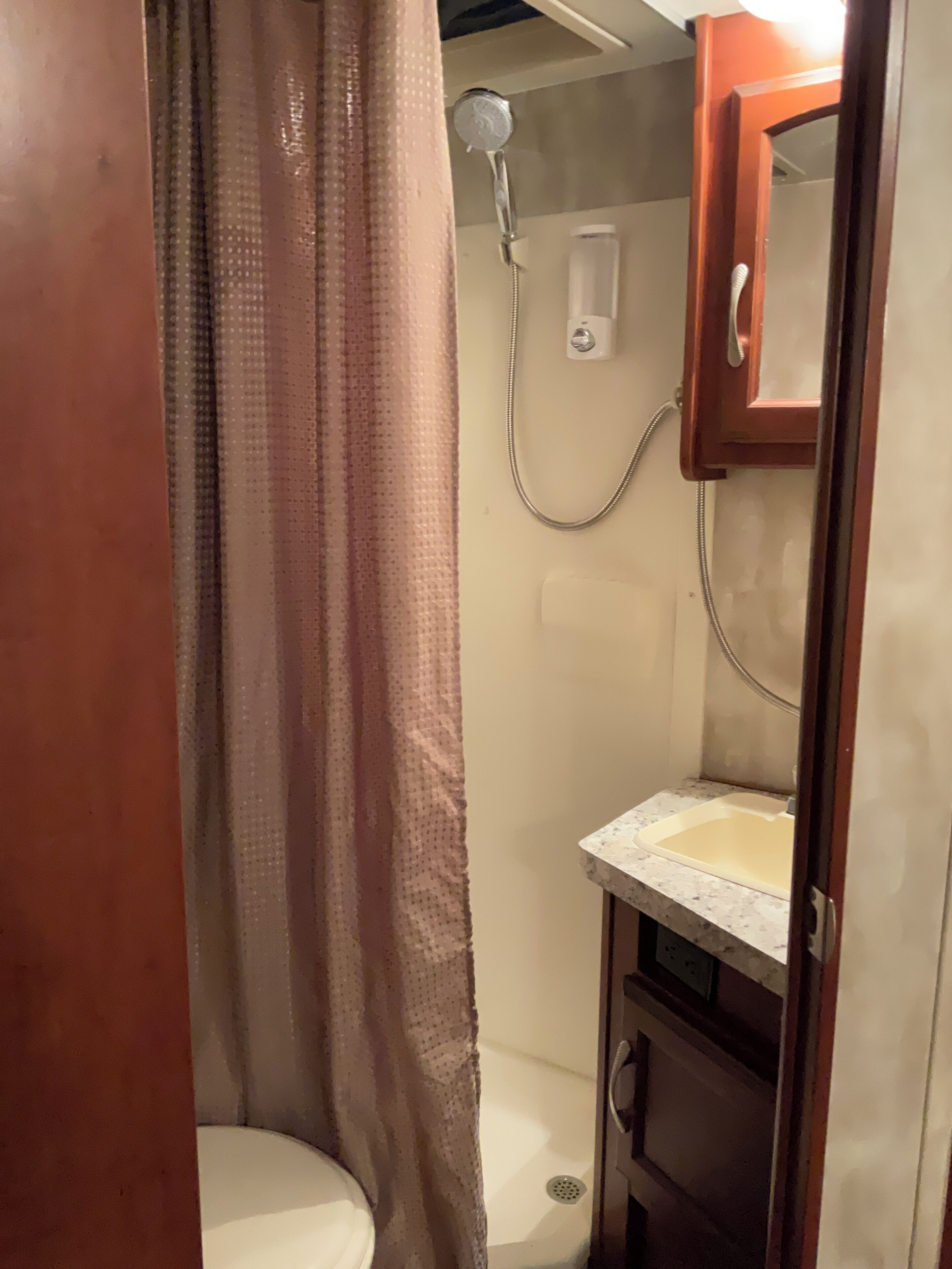 A bathroom with a shower, toilet, and sink.