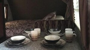 Een gezellig eethoekje met een tafel gedekt voor twee personen, inclusief kommen, borden en glazen.