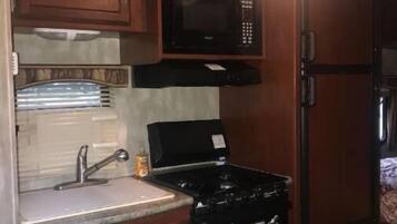Una cocina compacta equipada con microondas, estufa, fregadero y armarios.