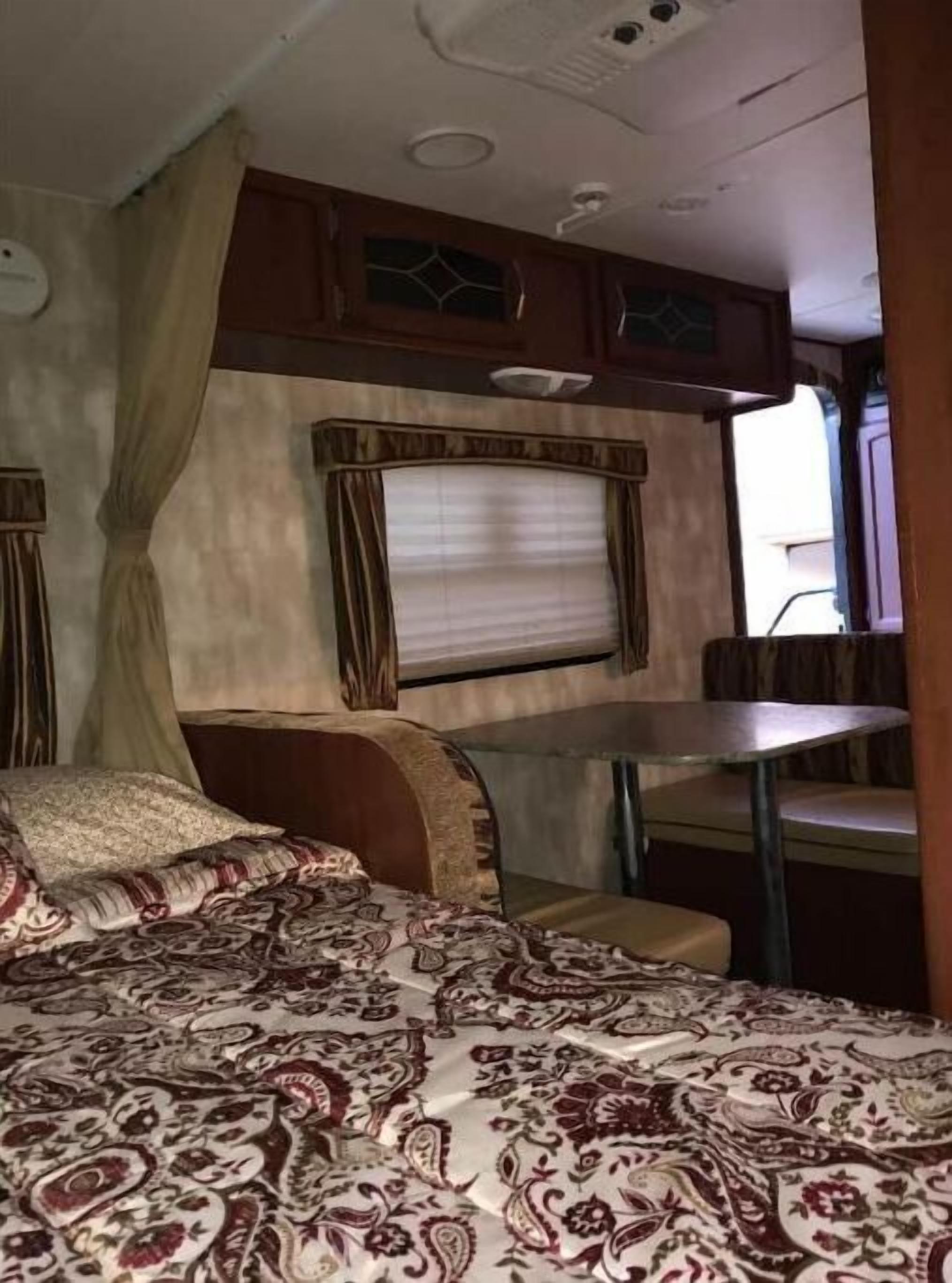 A cozy RV interior with a bed, a table, and a window.