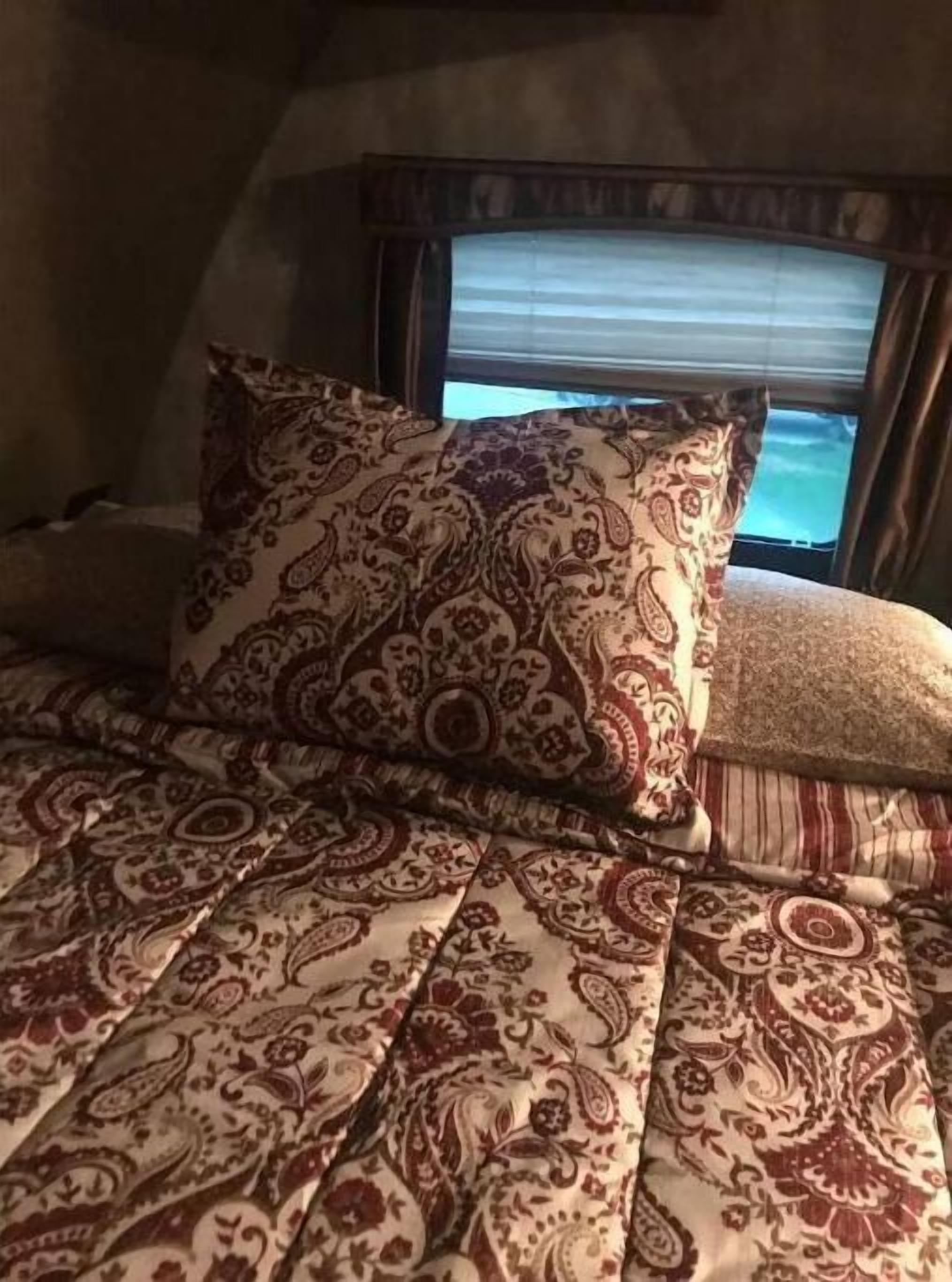 Ein Bett mit einem gemusterten Überwurf und einem Zierkissen.