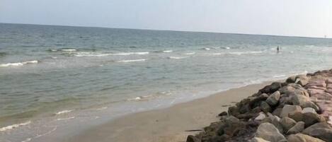 A beach with a rocky shoreline and calm waves.