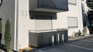 A modern building with a large, flat facade, a prominent number '33' on the side, and a balcony with a metal railing. - Vacation apartments Gergert (Löwenstein)