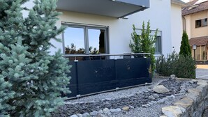 A modern building with a large window, a rock garden, and a metal fence. - Vacation apartments Gergert (Löwenstein)