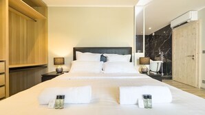 A neatly made bed with white linens, two bedside lamps, and a wooden wardrobe. - Le First (Cannes)