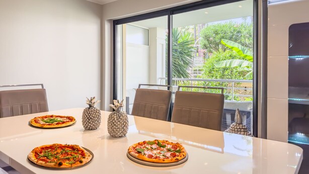 A dining table with three pizzas, two pineapple-shaped salt and pepper shakers, and a decorative salt shaker. - Le First (Cannes)