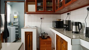 A kitchen with wooden cabinets, a microwave, a coffee maker, and a small countertop. - Sleek, Beautiful  and Private Cottage (Arusha)