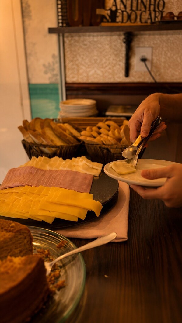 Montaje de bufé con distintos alimentos y una persona sirviéndose.
