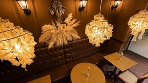 A dimly lit lounge area with a brown leather sofa, round tables, and wall-mounted lamps. - Vivaz Boutique Hotel (Recife)
