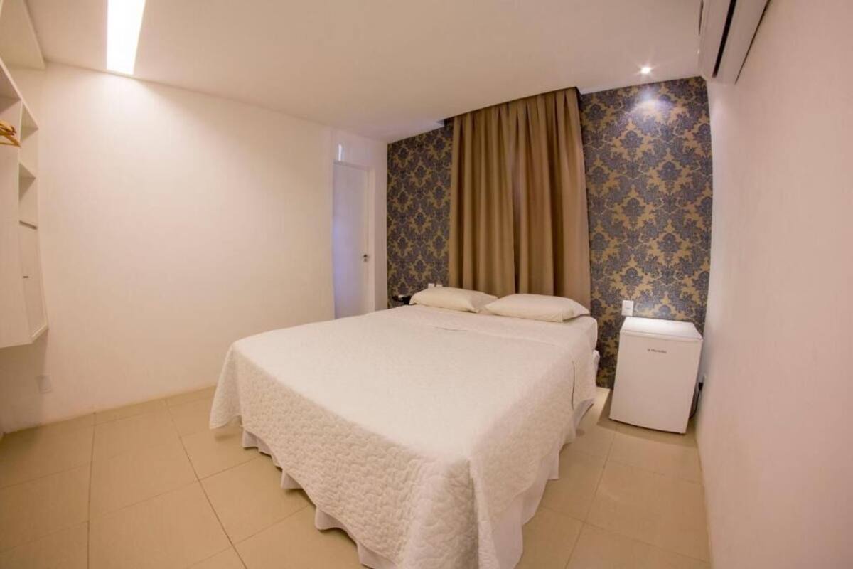 A bedroom with a bed, a wardrobe, and a small white appliance.